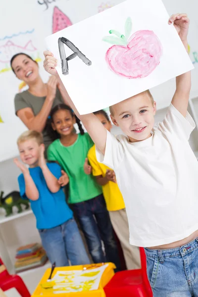 Menino jardim de infância orgulhoso segurando pintura alta — Fotografia de Stock