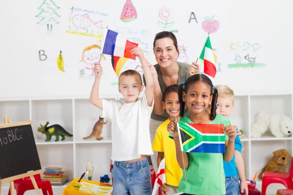 Niños en edad preescolar y maestro con banderas en el aula — Foto de Stock