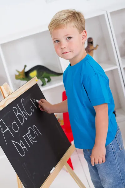 Menino pré-escolar na frente de quadro-negro — Fotografia de Stock