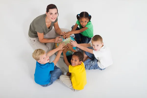 Дошкольный учитель и ученики руки на глобусе — стоковое фото