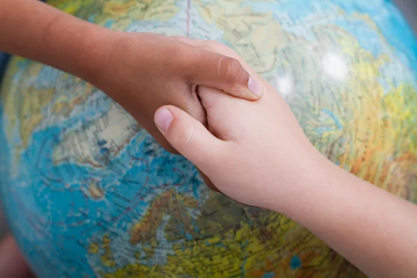 Kids handshake on globe — Stock Photo, Image