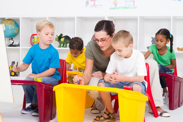 Preschool students and female teacher in kindergarten