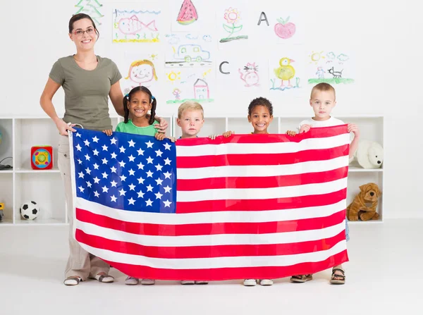 Αμερικανική τους μαθητές προσχολικής αγωγής και δάσκαλος, κρατώντας μια σημαία των ΗΠΑ — Φωτογραφία Αρχείου