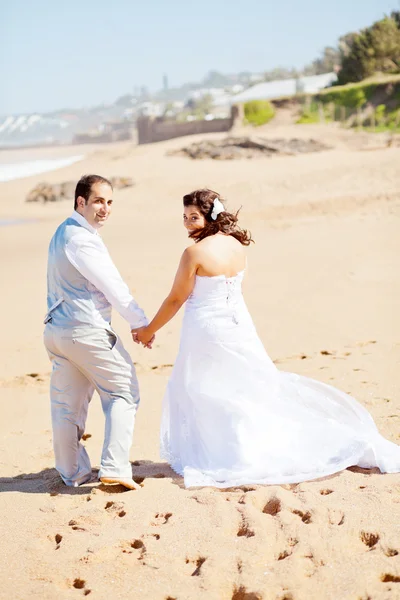 Невеста и жених прогуливаются по пляжу — стоковое фото