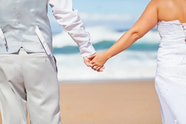 Novio y novia tomados de la mano en la playa — Foto de Stock