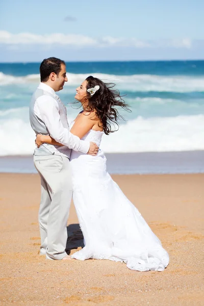 Noivo e noiva abraçando na praia — Fotografia de Stock