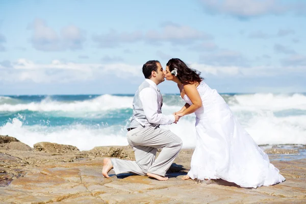 Bruid en bruidegom kussen op strand rotsen — Stockfoto