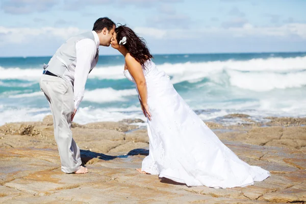 Bräutigam und Braut küssen sich am Strand — Stockfoto