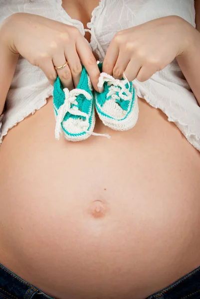 Abdômen de mulheres grávidas e botas de malha — Fotografia de Stock