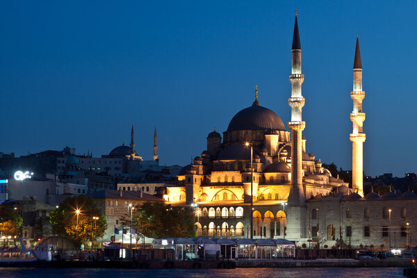 Istanbul skyline from Galata bridge by night, with Suleymaniye mosque and fish boat restaurants in Eminonu