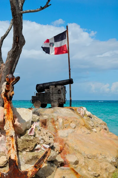 Vieux canon en fonte, et l'ancre du navire devant le drapeau de la République dominicaine sur la côte atlantique — Photo