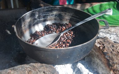 Roasting coffee beans in a pan en plantation in the Dominican Republic clipart
