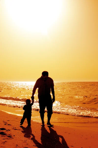 Dziecko z ojcem na morzu na zachód słońca — Zdjęcie stockowe