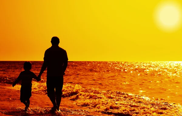 Dziecko z ojcem na morzu na zachód słońca — Zdjęcie stockowe