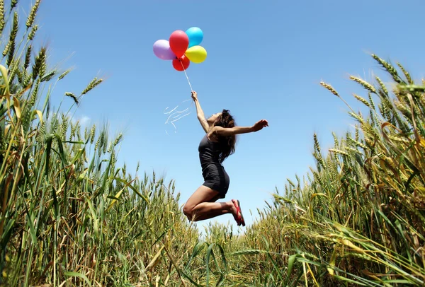 Młoda kobieta z kolorowych balonów w polu — Zdjęcie stockowe