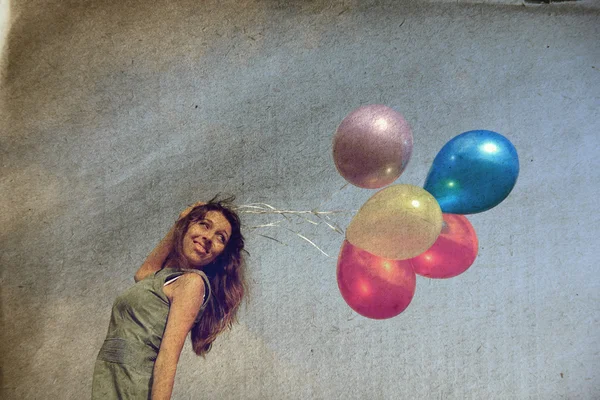 Ung kvinna håller färgglada ballonger och flyger över en äng. Foto i gammal färg bilden stil. — Stockfoto