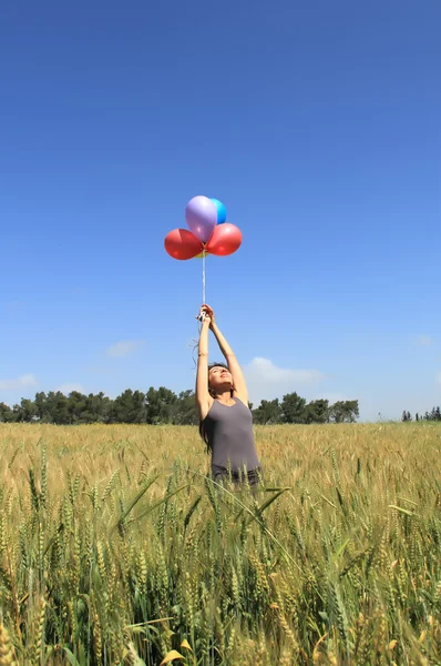 Mujer joven con globos de colores en el campo — Foto de Stock