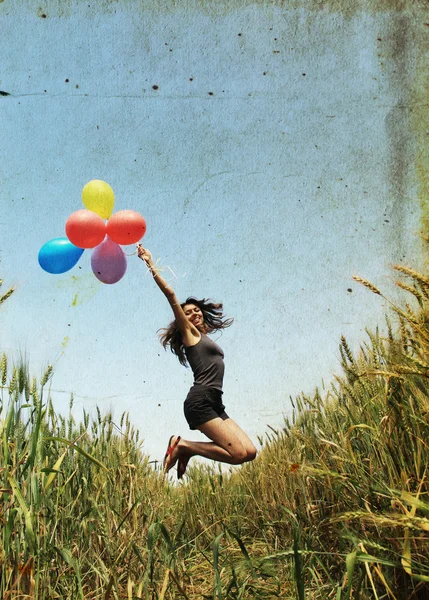 Молодая женщина с разноцветными воздушными шарами в поле — стоковое фото