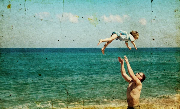 Far och son spelar tillsammans på stranden — Stockfoto