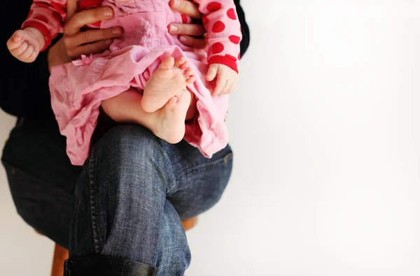Annesinin elleri üzerinde oturan pembe elbiseli küçük kız — Stok fotoğraf