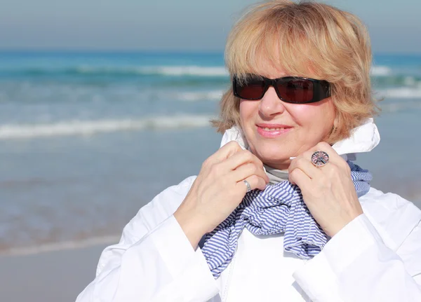 Senior vrouw met armen gestrekt op winter strand — Stockfoto