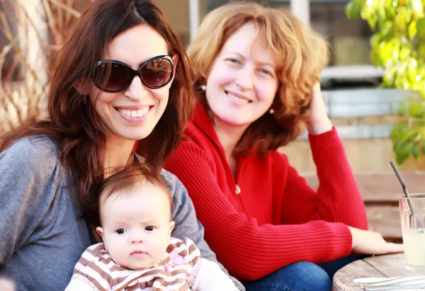 Zwei schöne Mädchen mit einem Baby im Freien — Stockfoto