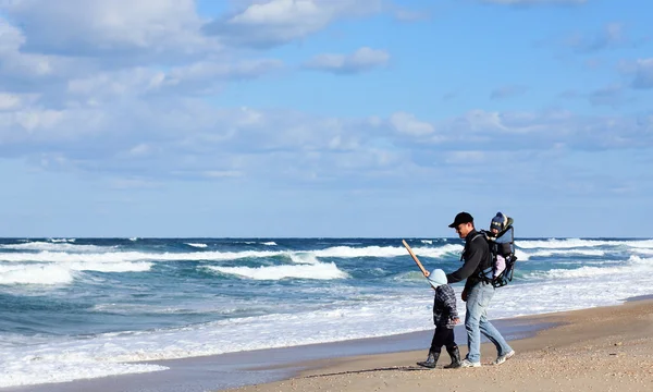 Papai com uma criança pequena andando em uma praia de inverno . — Fotografia de Stock