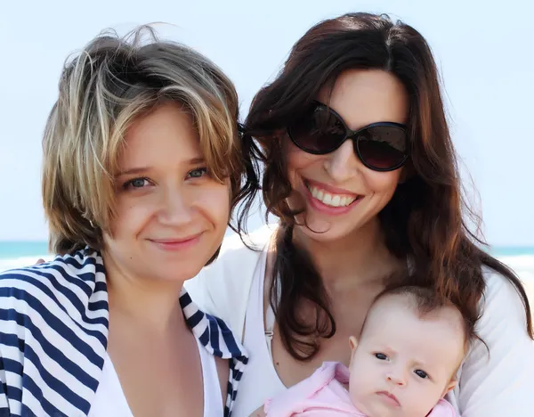Две красивые девушки с ребенком на пляже — стоковое фото