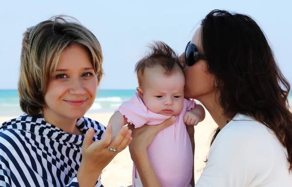 Dos hermosas chicas con un bebé en la playa — Foto de Stock