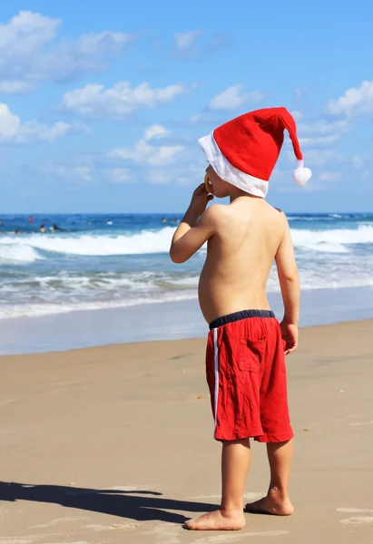 Garçon de 4 ans dans le chapeau du Père Noël sur la plage — Photo
