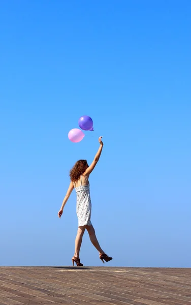 Genç kız yürüyor ve balonlar dalgalar — Stok fotoğraf