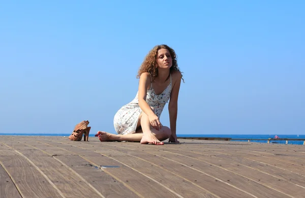 Jong meisje, zittend op een houten pier — Stockfoto