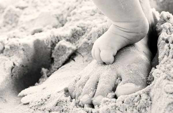 Moeder en baby's voeten op het strand — Stockfoto