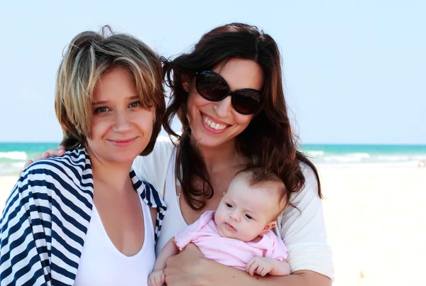 Two beautiful girls with a baby on the beach — Stock Photo, Image