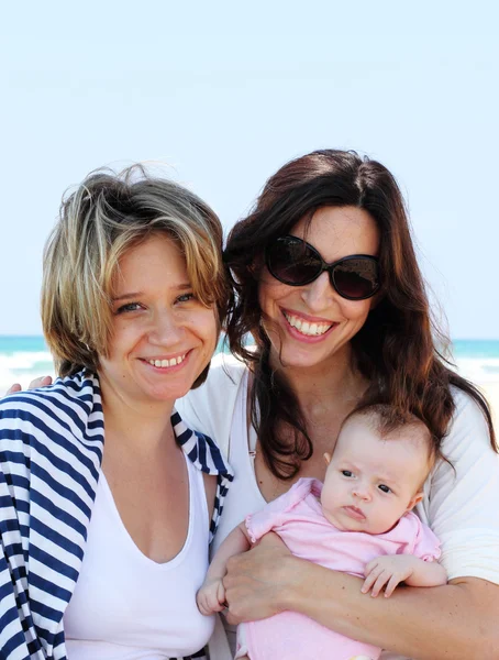 Duas meninas bonitas com um bebê na praia — Fotografia de Stock
