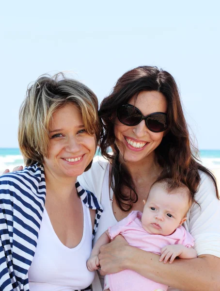 Two beautiful girls with a baby on the beach — Stock Photo, Image