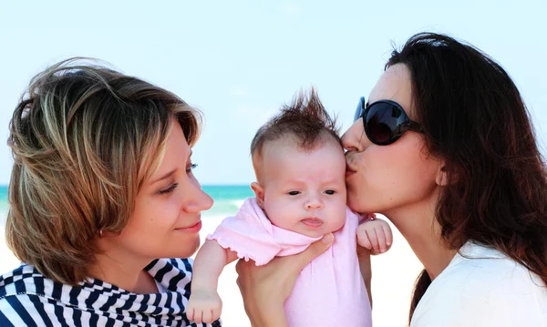 Two beautiful girls with a baby on the beach — Stock Photo, Image