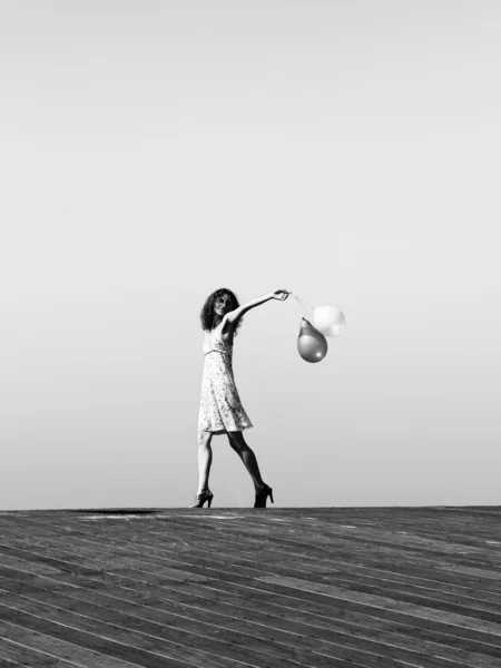 Молода дівчина йде з повітряними кулями на фоні блакитного неба — стокове фото
