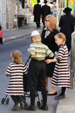 Children and adults dressed in traditional Jewish clothing, cross the road clipart