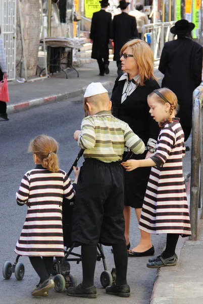 Kinder und Erwachsene in traditioneller jüdischer Kleidung überqueren die Straße — Stockfoto