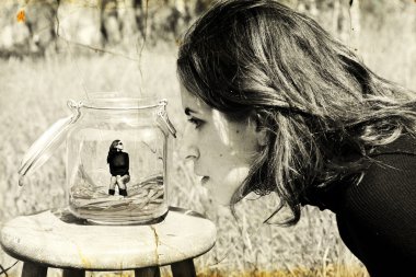 Girl looks at herself in the glass jar. Photo in old image style clipart