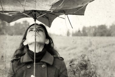 Girl with umbrella in the field. Photo in old color image style. clipart