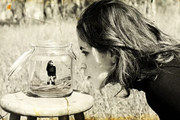 Girl looks at herself in the glass jar. Photo in old image style — Stock Photo, Image