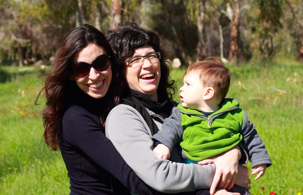 Two beautiful girls with a baby in the background of the spring — Stock Photo, Image