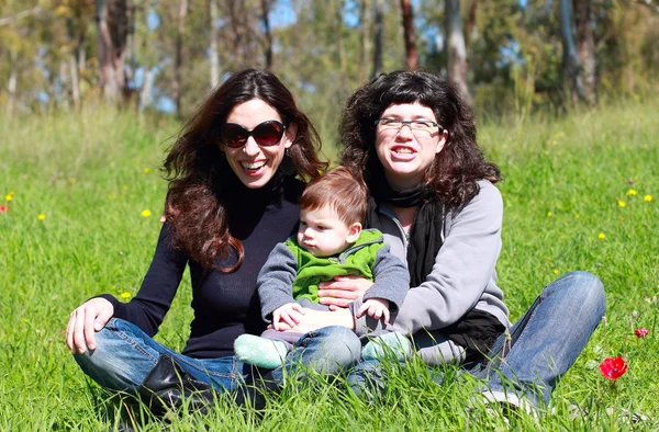 Twee mooie meisjes met een baby op de achtergrond van de lente — Stockfoto