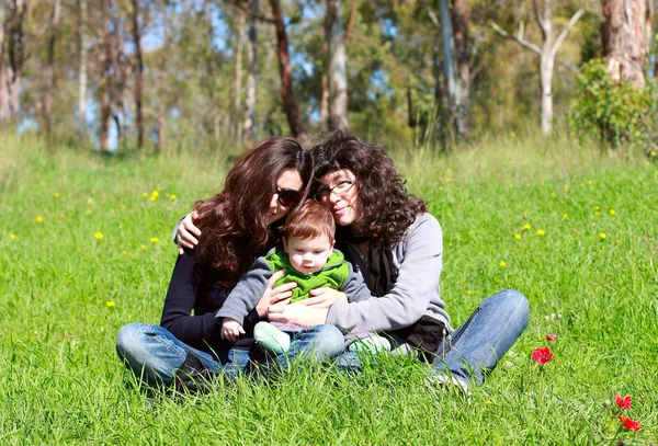 Two beautiful girls with a baby in the background of the spring — Stock Photo, Image