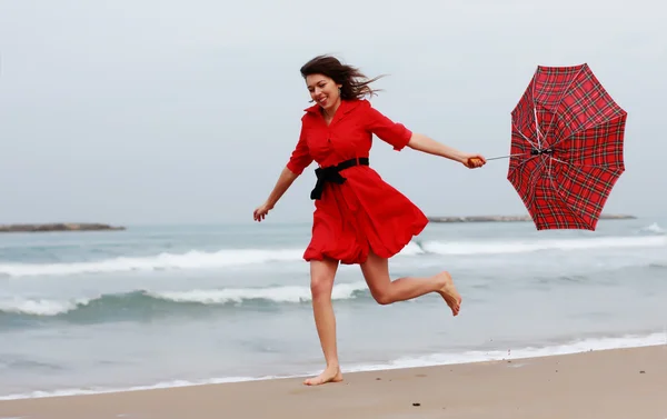 Beautiful girl in red dress on the winter beach — Stock Photo, Image