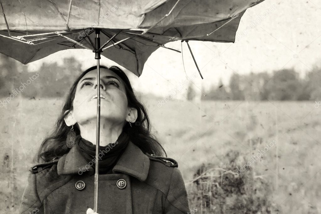 Girl with umbrella in the field. Photo in old color image style.