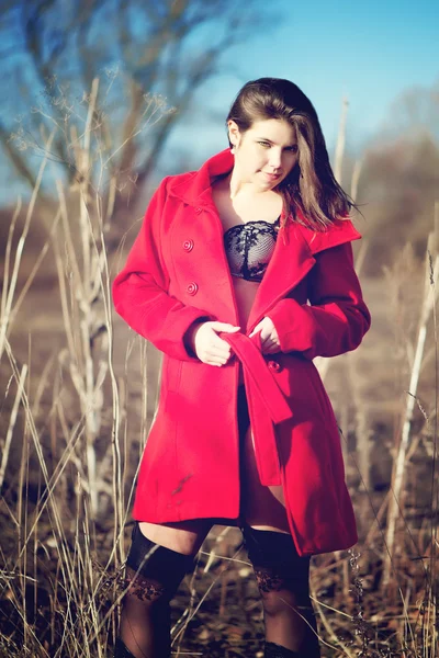 Брюнетка в красном пальто с бельем на открытом воздухе — стоковое фото