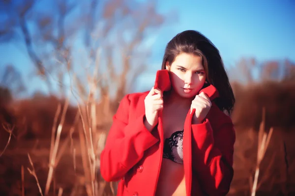 Brunette woman in red coat with underwear outdoor — Stock Photo, Image